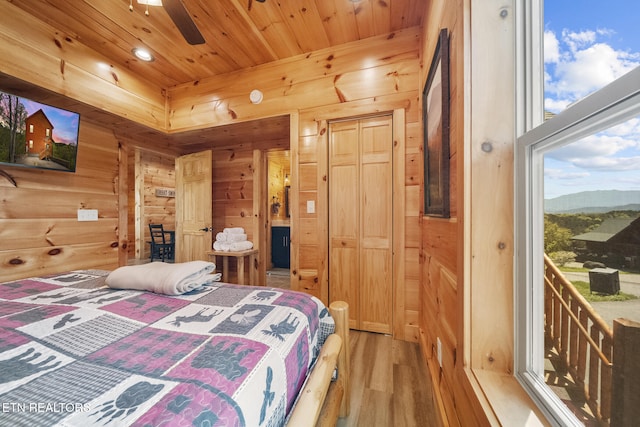 bedroom with wood ceiling, wooden walls, and multiple windows