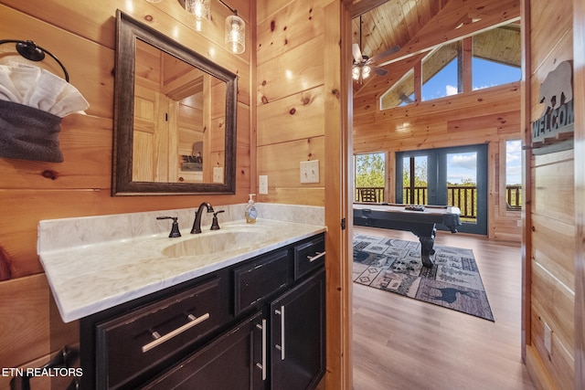 bathroom with wood walls, vanity, beam ceiling, and wood finished floors