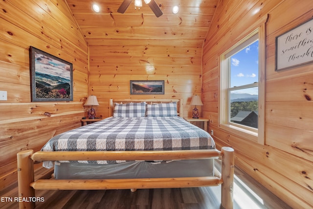 bedroom featuring lofted ceiling, wood walls, a ceiling fan, and wood finished floors