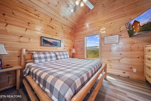 bedroom featuring wood walls, vaulted ceiling, and wood finished floors