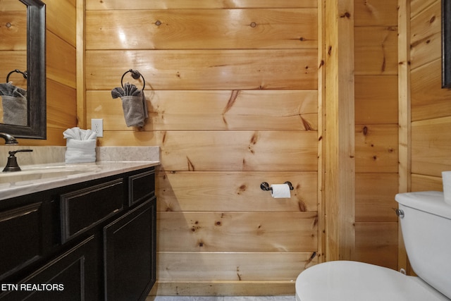 half bath with wood walls, vanity, and toilet