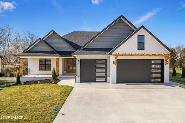 modern farmhouse with covered porch, driveway, a front lawn, and a shingled roof