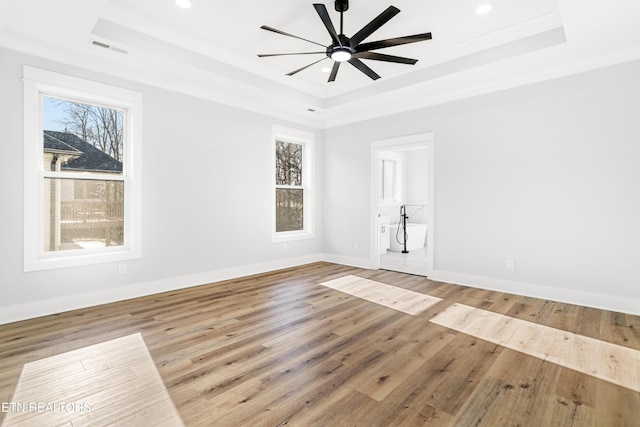 unfurnished room with visible vents, a tray ceiling, and a wealth of natural light