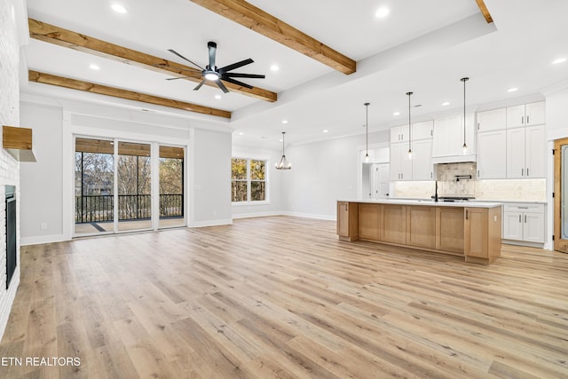 kitchen with tasteful backsplash, light countertops, a glass covered fireplace, open floor plan, and light wood-type flooring