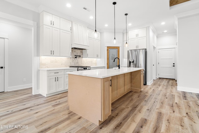 kitchen featuring stove, visible vents, light countertops, backsplash, and stainless steel fridge