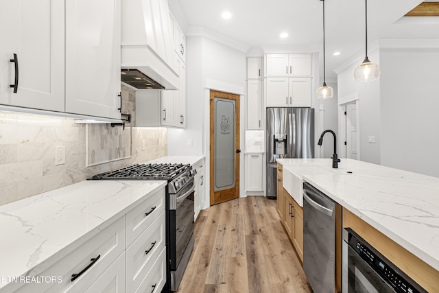 kitchen with stainless steel appliances, a sink, white cabinetry, light wood-type flooring, and pendant lighting