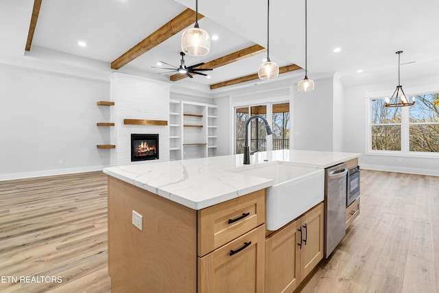 kitchen with a sink, light wood finished floors, open floor plan, and stainless steel dishwasher