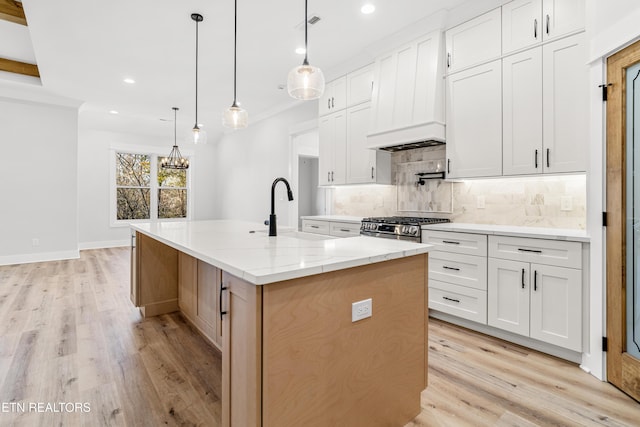 kitchen featuring a center island with sink, recessed lighting, backsplash, light wood-style floors, and a sink