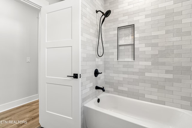 bathroom featuring wood finished floors, bathtub / shower combination, and baseboards