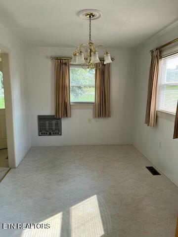 unfurnished dining area featuring a chandelier, visible vents, and heating unit