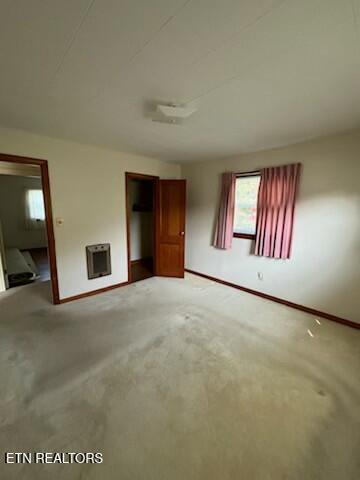 interior space featuring heating unit, baseboards, and light colored carpet