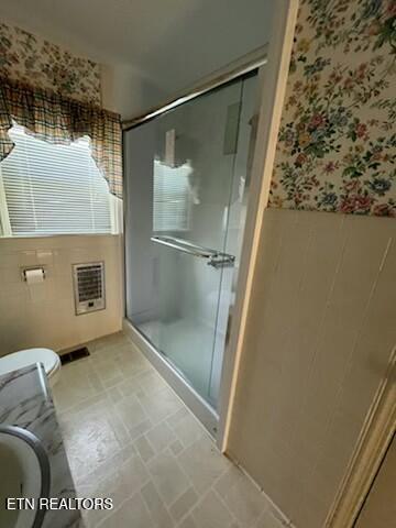 bathroom with toilet, a wainscoted wall, wallpapered walls, and a stall shower