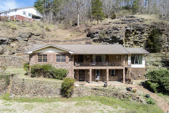 view of front of house featuring a patio area, brick siding, and a chimney