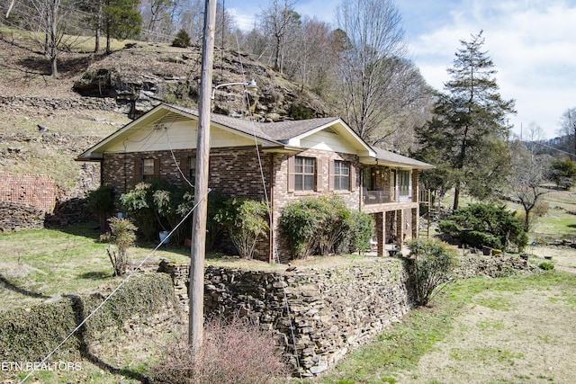 view of home's exterior with stairway, brick siding, and a yard