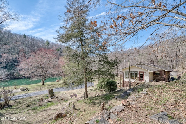 exterior space featuring a forest view and a chimney