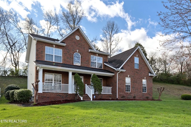 traditional-style home with brick siding, a porch, and a front yard