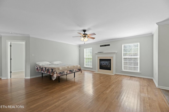 living area featuring a healthy amount of sunlight, light wood-style flooring, a ceiling fan, and ornamental molding
