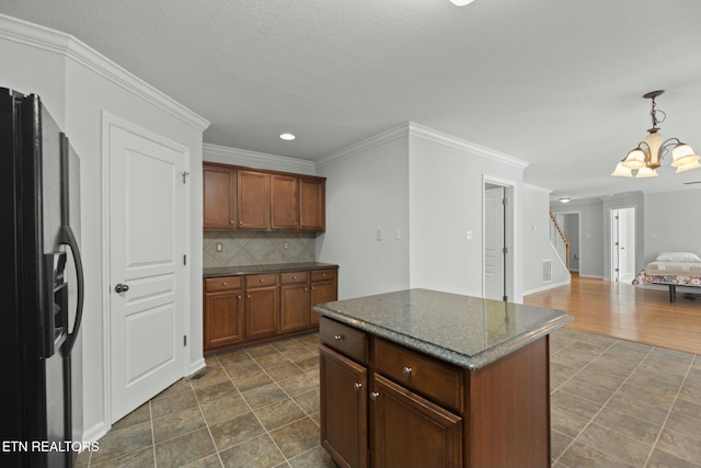 kitchen featuring ornamental molding, decorative backsplash, black fridge with ice dispenser, pendant lighting, and a chandelier