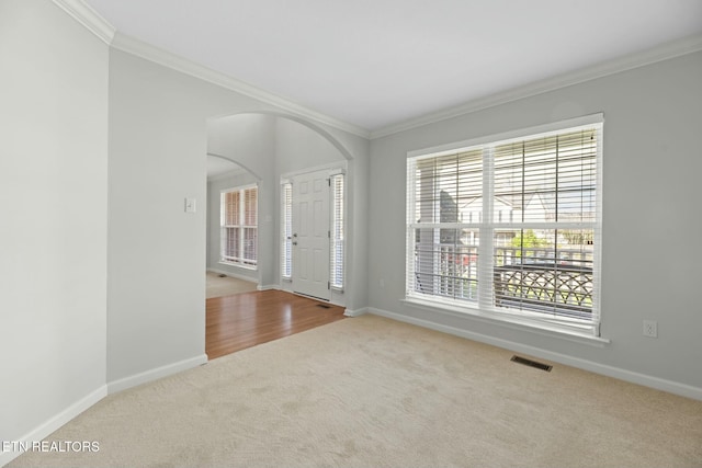 entryway with visible vents, ornamental molding, arched walkways, carpet, and baseboards