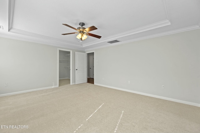 carpeted spare room with visible vents, crown molding, baseboards, ceiling fan, and a tray ceiling