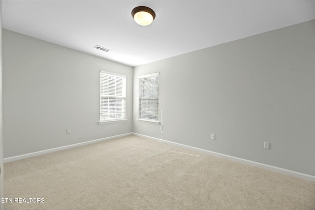empty room featuring visible vents, baseboards, and light colored carpet