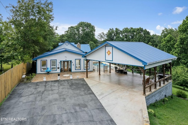 view of front of home featuring a carport, metal roof, fence, and driveway