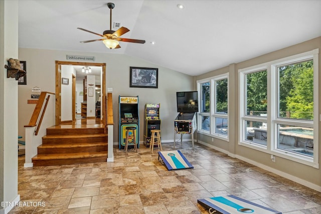 workout area featuring ceiling fan, stone finish flooring, baseboards, and vaulted ceiling