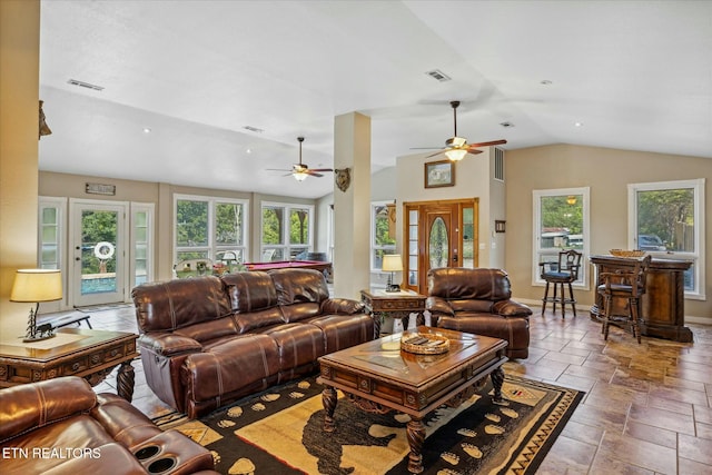 living area with lofted ceiling, stone tile floors, visible vents, and baseboards