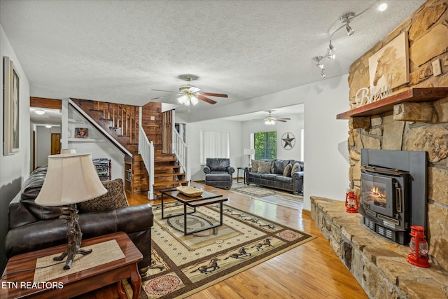 living room featuring a textured ceiling, stairway, and wood finished floors