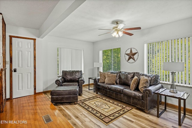 living room featuring visible vents, baseboards, a ceiling fan, wood-type flooring, and a textured ceiling