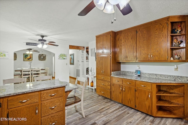 kitchen with light wood-style floors, open shelves, a textured ceiling, and brown cabinetry