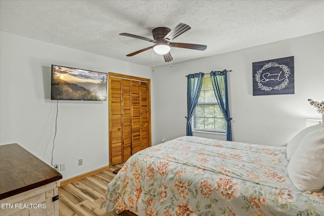 bedroom with a textured ceiling, ceiling fan, wood finished floors, baseboards, and a closet