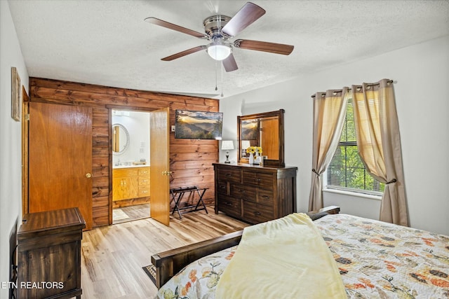 bedroom with ceiling fan, a textured ceiling, light wood finished floors, and ensuite bath