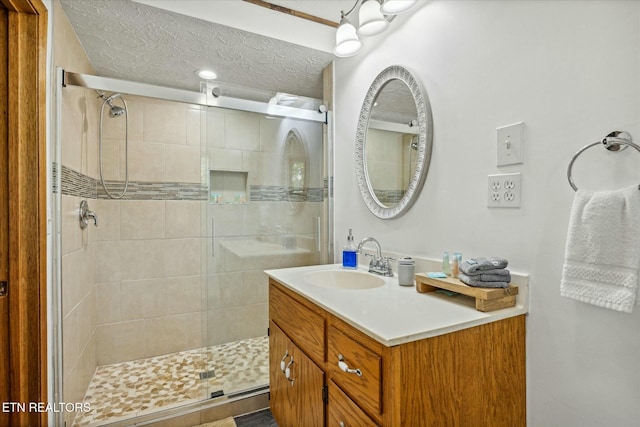 full bath with a shower stall, a textured ceiling, and vanity