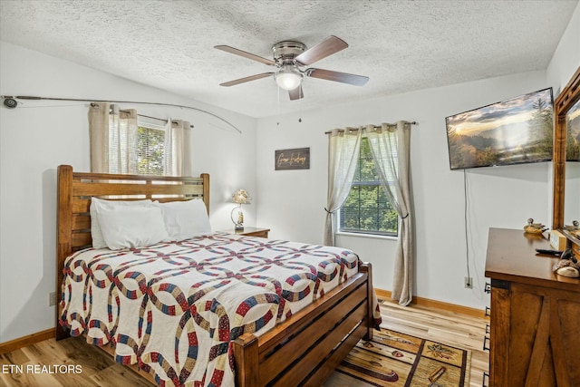 bedroom featuring a textured ceiling, multiple windows, and light wood-type flooring