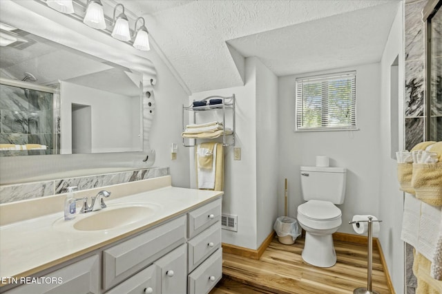 bathroom featuring visible vents, toilet, wood finished floors, a textured ceiling, and a shower stall