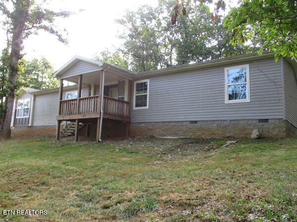 back of property with crawl space, stairway, a lawn, and a wooden deck