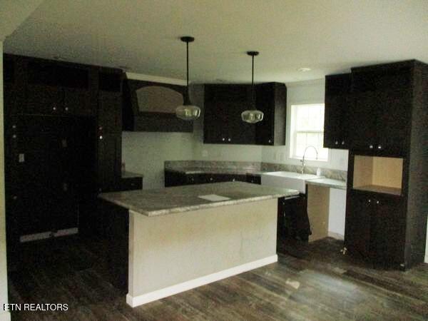 kitchen featuring dark wood-type flooring, a center island, pendant lighting, and a sink