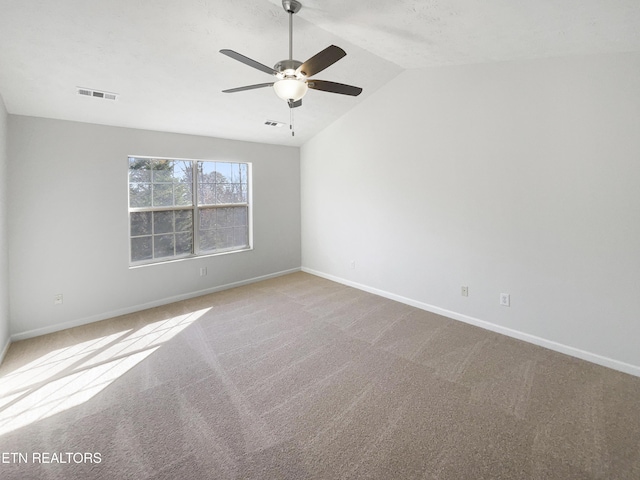 carpeted spare room featuring a ceiling fan, visible vents, vaulted ceiling, and baseboards