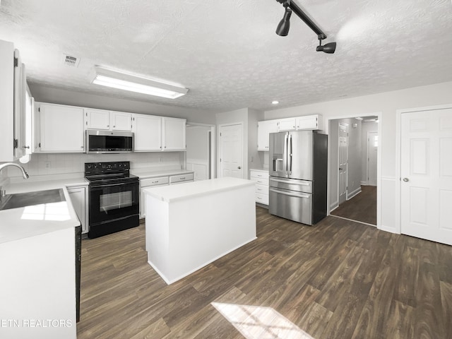 kitchen featuring appliances with stainless steel finishes, dark wood-style flooring, a kitchen island, and a sink