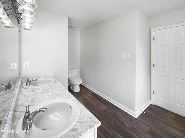 full bath featuring double vanity, a sink, baseboards, and wood finished floors