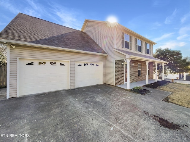 view of front facade with driveway, a shingled roof, a garage, and a porch