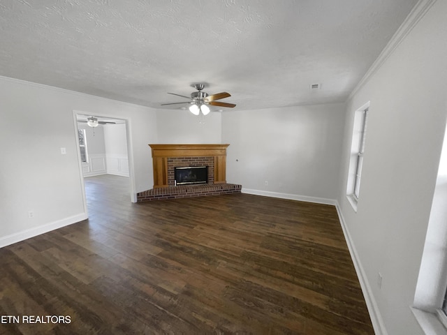 unfurnished living room with a brick fireplace, a textured ceiling, a ceiling fan, and dark wood-type flooring