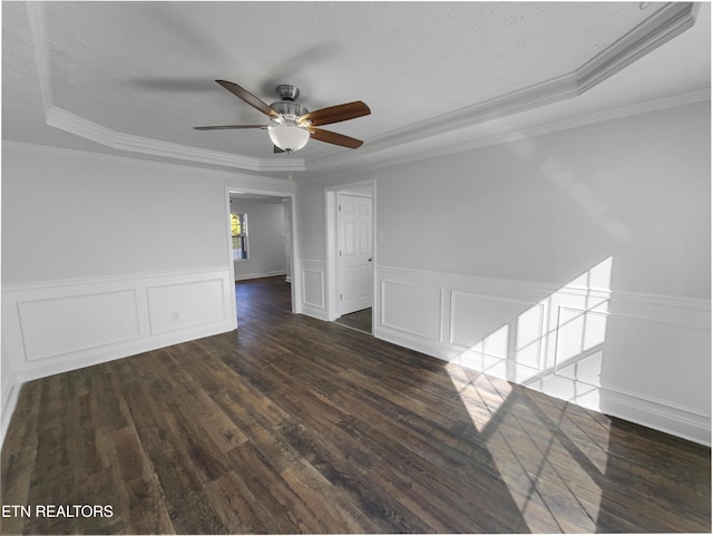 spare room featuring ornamental molding, a raised ceiling, wainscoting, and wood finished floors