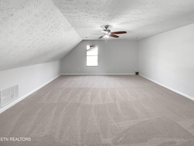 bonus room with carpet floors, baseboards, visible vents, and a textured ceiling