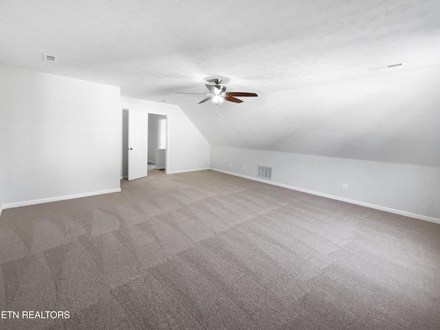 additional living space featuring lofted ceiling, visible vents, and a textured ceiling