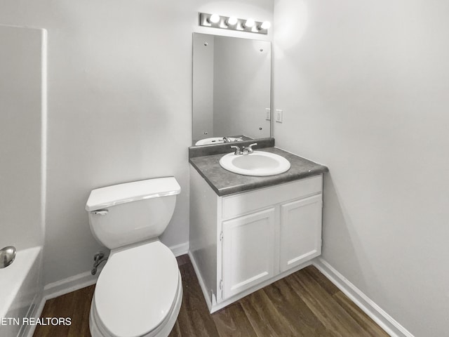 bathroom with vanity, wood finished floors, toilet, and baseboards