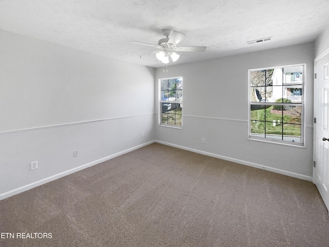 carpeted empty room featuring visible vents, ceiling fan, a textured ceiling, and baseboards