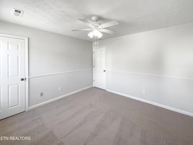 unfurnished room with carpet, visible vents, a ceiling fan, a textured ceiling, and baseboards