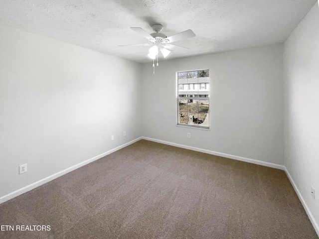 unfurnished room with a ceiling fan, dark carpet, a textured ceiling, and baseboards